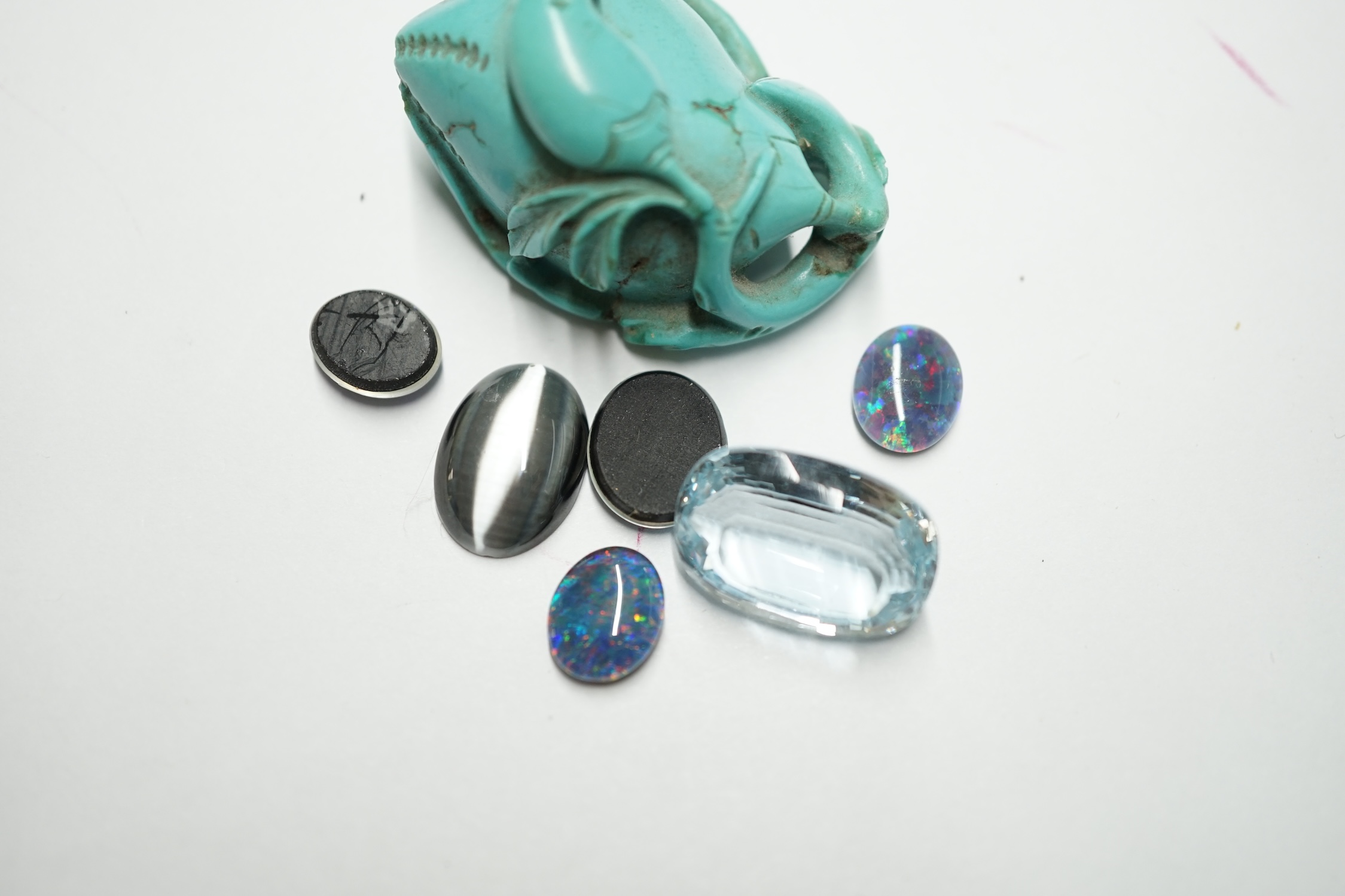 A turquoise carving and a small group of unmounted stones including opal doublets and chatoyant and a blue topaz. Condition - fair